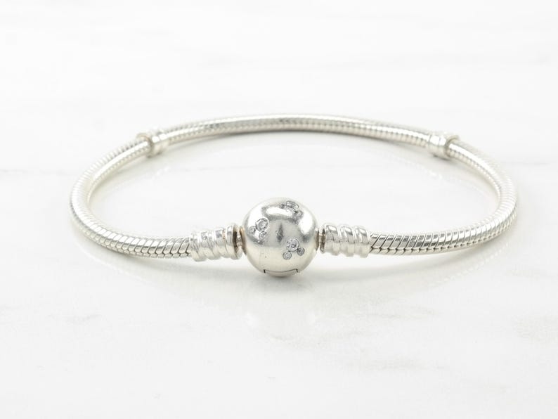 A silver bracelet with a round charm in the center.