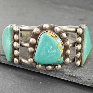 A silver bracelet with turquoise stones and metal studs.