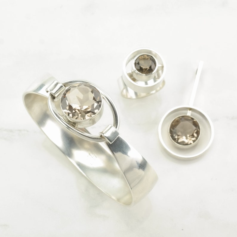 Peut inclure: Un ensemble de trois bijoux en argent avec des pierres de quartz fum&eacute;. L'ensemble comprend un bracelet, une bague et un pendentif.