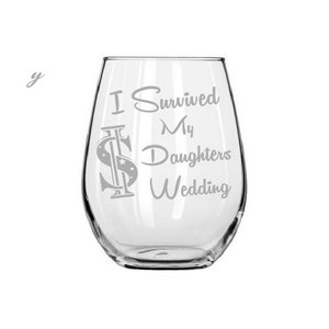 May include: A clear glass wine glass with the text "I Survived My Daughters Wedding" etched on the side. The text is in a stylized font with a dollar sign graphic.