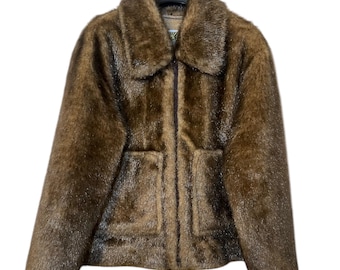 May include: A brown faux fur jacket with a zipper closure and two large pockets. The jacket has a collar and is hanging on a black hanger.