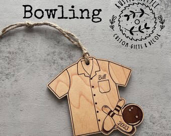 Puede incluir: Un adorno de madera de camisa de bolos con el nombre "Bill" en el bolsillo, dos bolos y una bola de bolos. El adorno está decorado con el año "2023" y el texto "Rustic Restyle Custom Gifts & Decor".