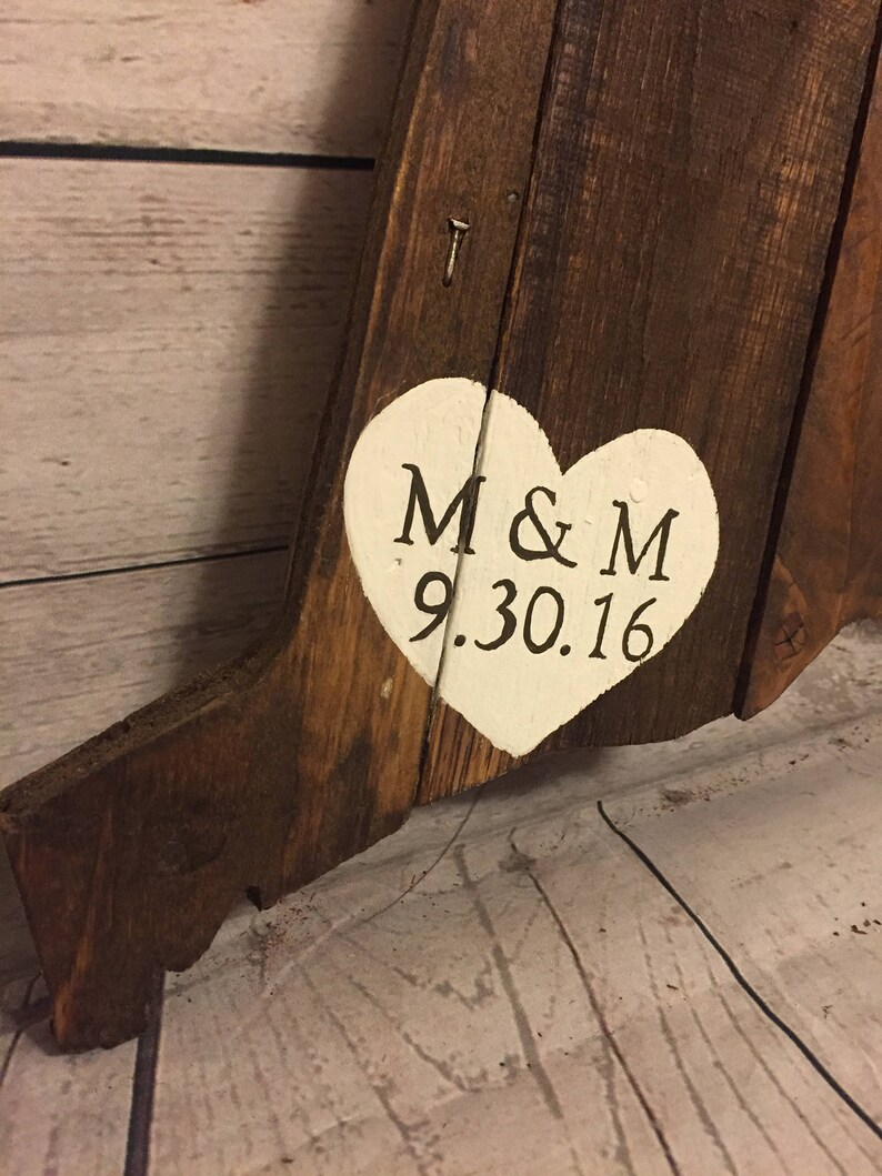 May include: A wooden sign with a white heart painted on it. The heart has the initials "M & M" and the date "9.30.16" written in black.
