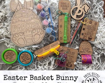 May include: Easter basket bunny egg stuffer kit with a wooden bunny egg paint-by-number, a wooden bunny ear ornament, a wooden sign that says "You add color to my world", a wooden sign that says "I'm wheelie glad it's Easter", a wooden sign that says "Slappin' into Easter", a wooden sign that says "Have a bubbly day!" with a bubble wand, a zip zip horray toy, two containers of play dough, and a set of paints.