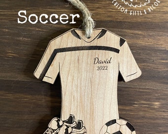 May include: Wooden soccer ornament with a soccer jersey, cleats, and a soccer ball. The ornament is personalized with the name "David" and the year "2022".