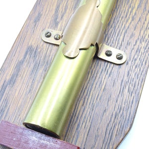 K&ouml;nnte beinhalten: Ein Messingteleskop, das auf einer Holztafel montiert ist. Das Teleskop ist mit einer Messinghalterung und Schrauben befestigt. Die Tafel hat eine dunkle Holzmaserung.