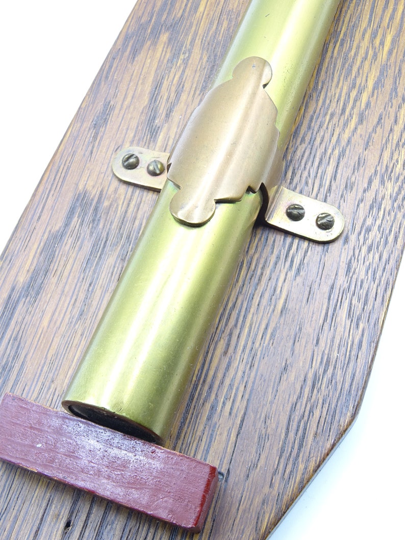 K&ouml;nnte beinhalten: Ein Messingteleskop, das auf einer Holztafel montiert ist. Das Teleskop ist mit einer Messinghalterung und Schrauben befestigt. Die Tafel hat eine dunkle Holzmaserung.