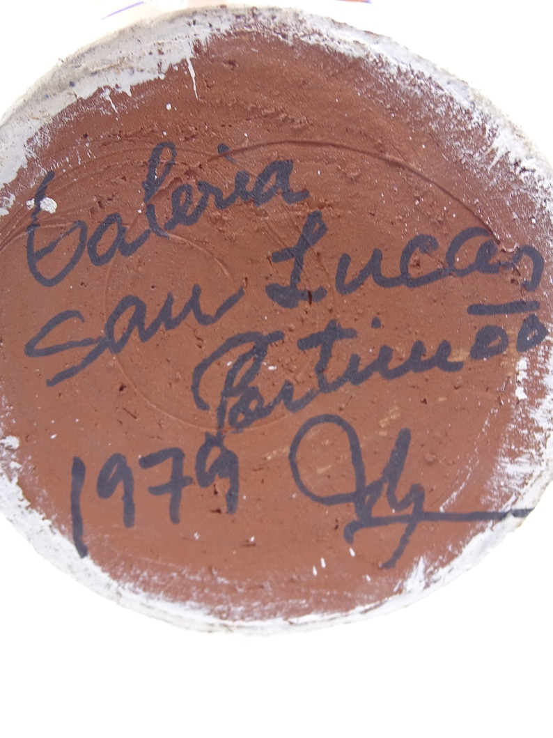May include: Close-up of the bottom of a ceramic vase with a brown glaze. The vase is signed "Galeria San Lucas" and dated "1979 July".