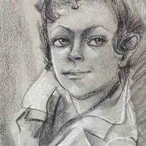 May include: A black and white charcoal drawing of a person's face. The person has short, curly hair and is wearing a collared shirt. The drawing is done in a realistic style.