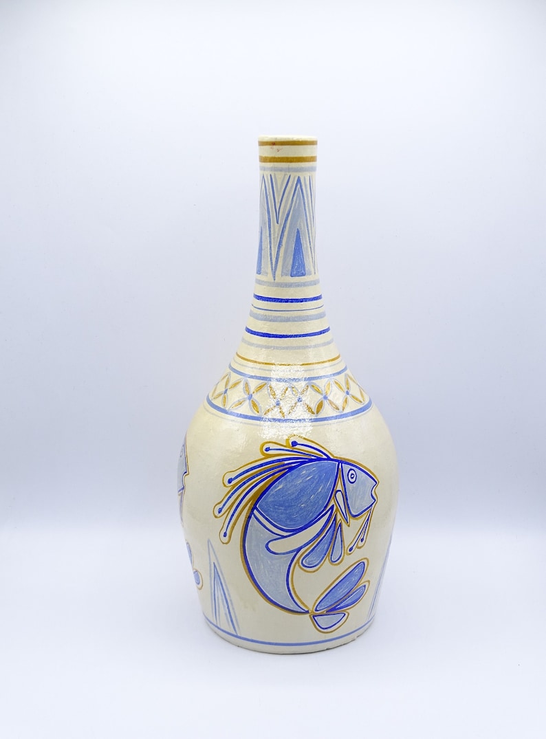 May include: A white ceramic vase with a blue and gold fish design. The vase has a narrow neck and a wide base.