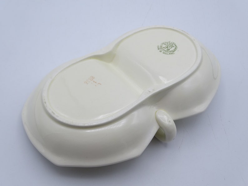 Może przedstawiać: Biała ceramiczna tacka do serwowania z dwoma podzielonymi sekcjami i uchwytem. Taca ma zielone oznaczenie na spodzie z napisem "Made in England".