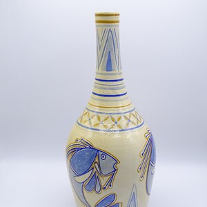 May include: A ceramic vase with a light yellow background and blue and gold painted fish designs. The vase has a narrow neck and a wide, rounded body.