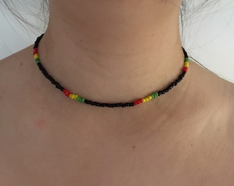 May include: A black beaded choker necklace with red, yellow, and green accents.