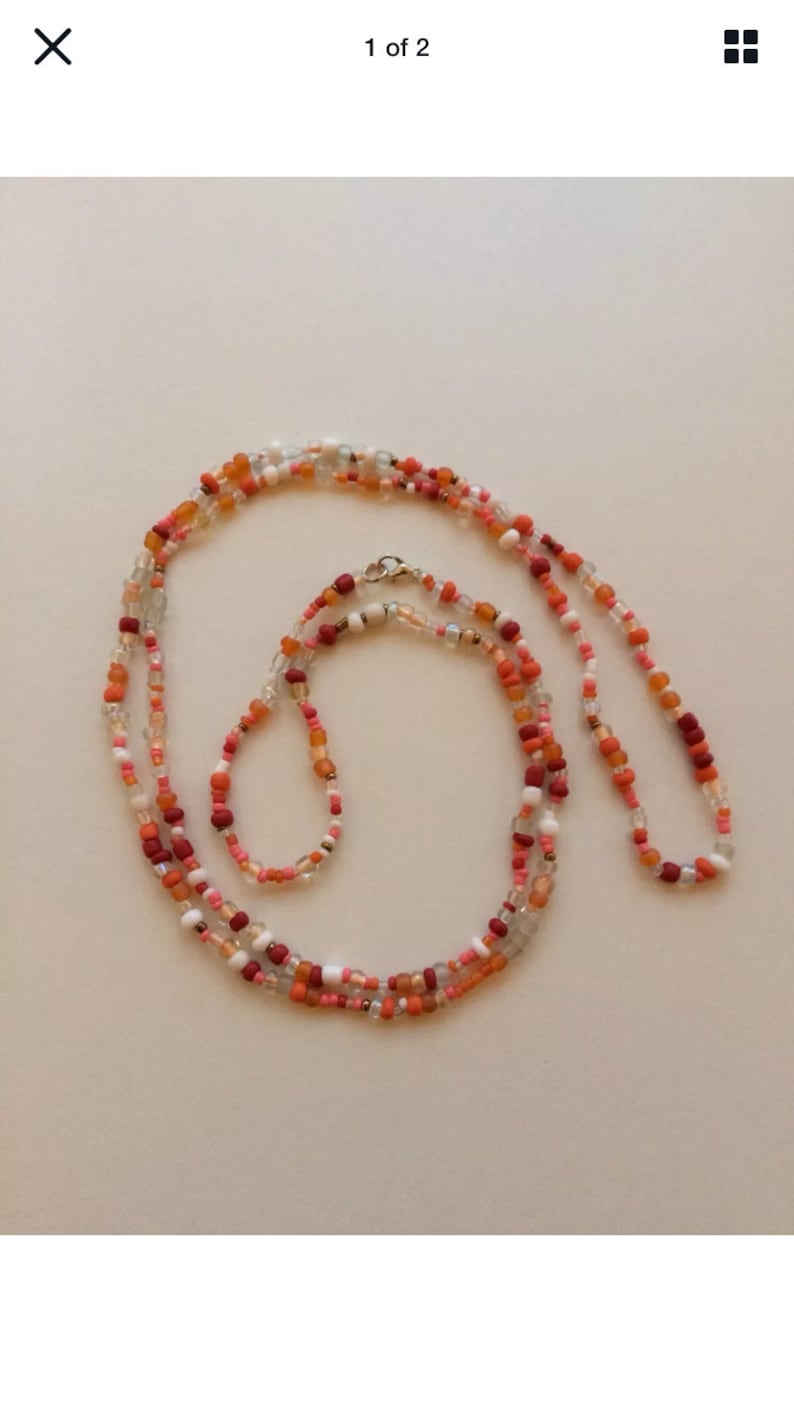 May include: A multi-strand beaded necklace featuring a blend of orange, red, white, and clear beads. The necklace is crafted from small, round beads and boasts a simple, elegant design.