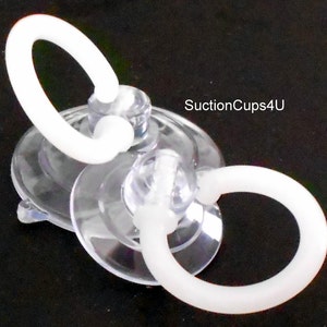 May include: Two clear suction cups with white plastic rings attached. The suction cups are designed to hold objects in place.