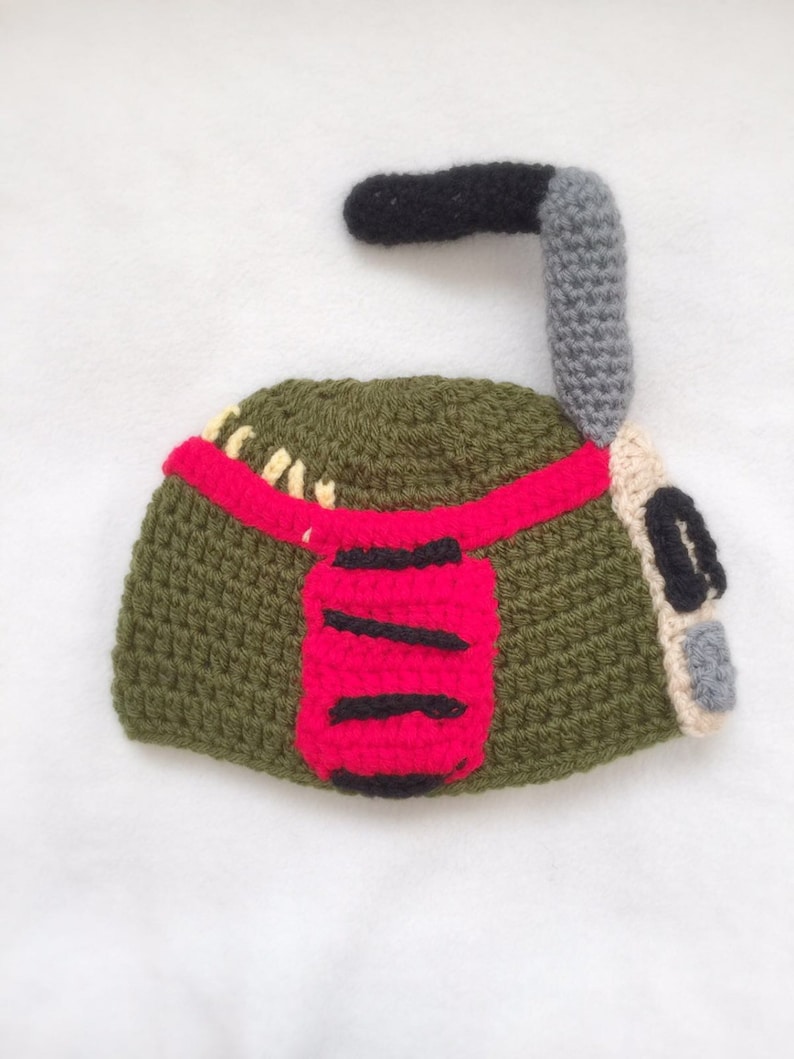 May include: Green, red, and gray crocheted hat shaped like a robot with a black antenna.