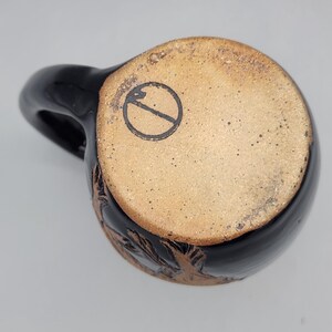 Puede incluir: Taza de cer&aacute;mica negra con cuerpo redondeado y asa. La base de la taza no est&aacute; esmaltada, con un dise&ntilde;o estampado. La taza tiene un dise&ntilde;o floral tallado alrededor de la base.