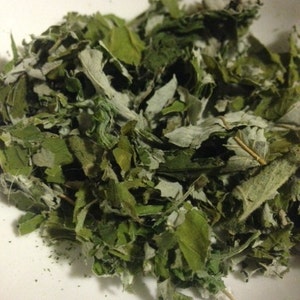 May include: A close-up of a pile of dried green leaves. The leaves are a mix of light and dark green, and some have a slightly silvery hue.