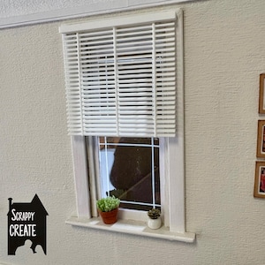May include: A miniature white window with white blinds, a white frame, and a windowsill. Two small potted succulents sit on the windowsill. The text "SCRAPPY CREATE" is on the left.