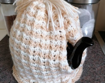 Beige and white striped knitted tea cosy