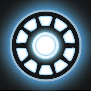 Może przedstawiać: Czarna tablica rejestracyjna z świecącym niebiesko-białym okrągłym wzorem. Wzór ma centralne koło otoczone pierścieniem segmentowych kształtów, które emitują miękkie niebieskie światło. Płyta ma cztery białe otwory montażowe.