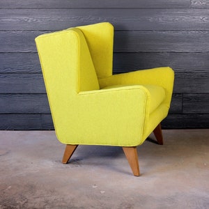 May include: A bright yellow armchair with a high back and wooden legs. The chair is upholstered in a textured fabric and has a modern design.