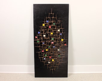 May include: A black wooden wall sculpture with a geometric design and colorful accents. The sculpture is made of wood and metal and features a variety of shapes and textures.