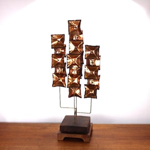 May include: A mid-century modern sculpture made of copper squares on a wooden base. The sculpture is abstract and has a geometric design.