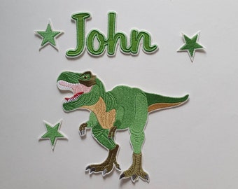 Puede incluir: Parche de dinosaurio verde bordado para planchar con el nombre "John" y cuatro estrellas verdes.