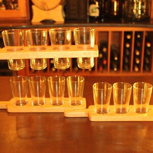 May include: A wooden serving tray with six clear glass beer mugs. The tray has a handle on each end and is designed to hold the mugs securely in place. The tray is made of natural wood and has a rustic look.