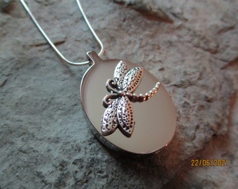 May include: Silver necklace with a round pendant featuring a detailed dragonfly design.