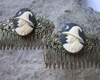 Op de afbeelding: Twee gouden haar kammen met zwarte en witte cameo heksenportretten. Elke cameo toont een heks met een puntige hoed en een halve maan op de achtergrond.