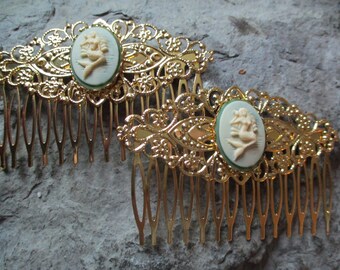 May include: Two gold hair combs with ornate designs and white cameo mermaids in green oval settings.