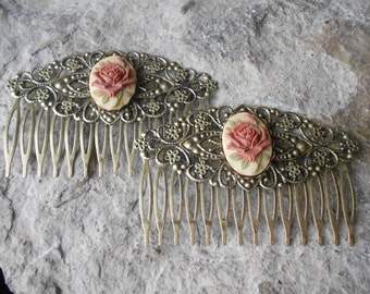 May include: Two gold hair combs with intricate filigree designs and a raised cameo of a pink rose.