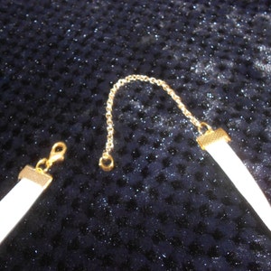 May include: A white choker necklace with a gold chain and clasp. The necklace is made of a soft, pliable material.