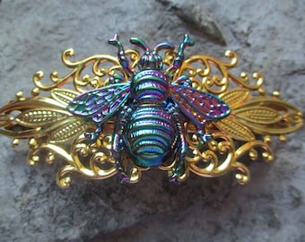 May include: A gold metal hair clip with an iridescent bee design. The bee has a detailed, textured body and wings.
