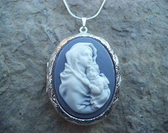 May include: A silver locket necklace with a blue cameo featuring a white image of the Virgin Mary holding a baby Jesus.