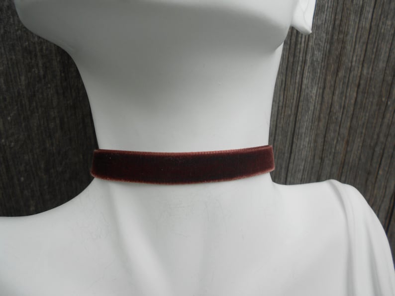 May include: A brown velvet choker necklace on a white mannequin.