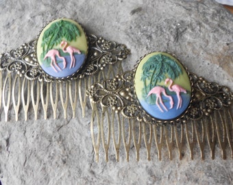 May include: Two gold hair combs featuring a pink flamingo and palm tree design. The combs are adorned with intricate filigree.