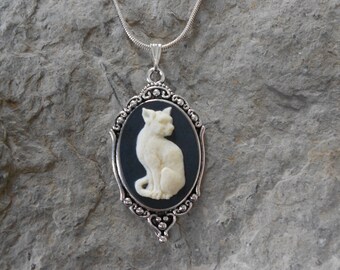 May include: A silver chain necklace with a black cameo pendant featuring a white cat silhouette.