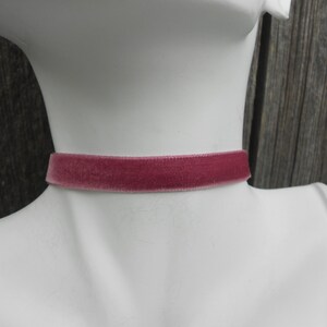 May include: A thin, dusty rose velvet choker necklace.