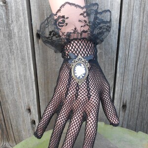 May include: Black fishnet gloves with a lace cuff and a decorative brooch featuring a white cameo.