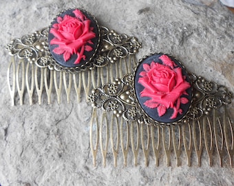 May include: Two gold hair combs with black and red cameo roses. Each comb has a detailed filigree design and a black oval cameo with a red rose.
