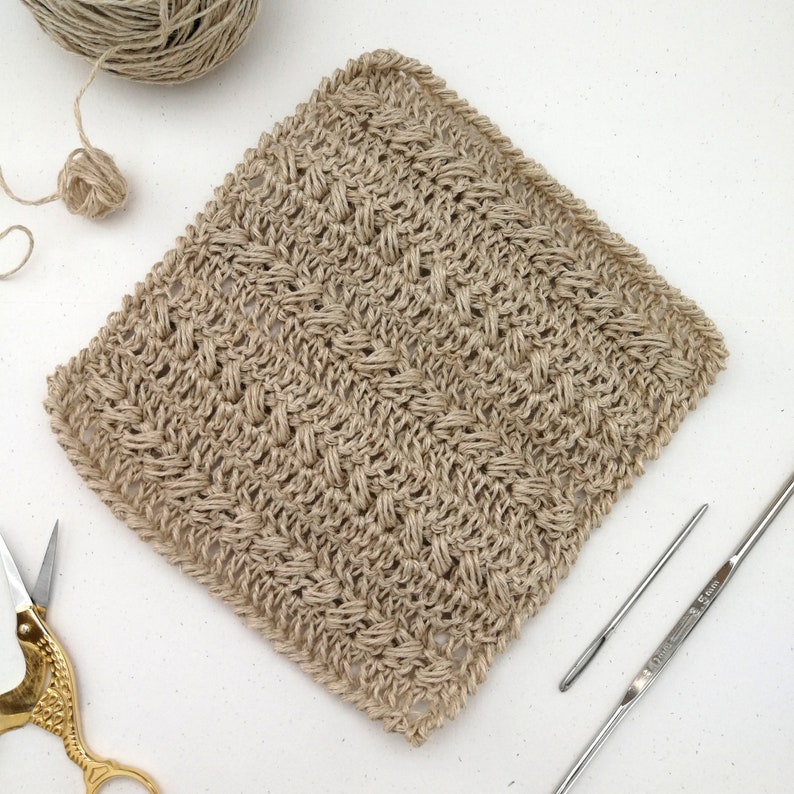 A birds eye view of a dishcloth made with the sport weight hemp. It is placed at an angle creating a diamond shape. The dishcloth has textured and is made using two alternating stitches.