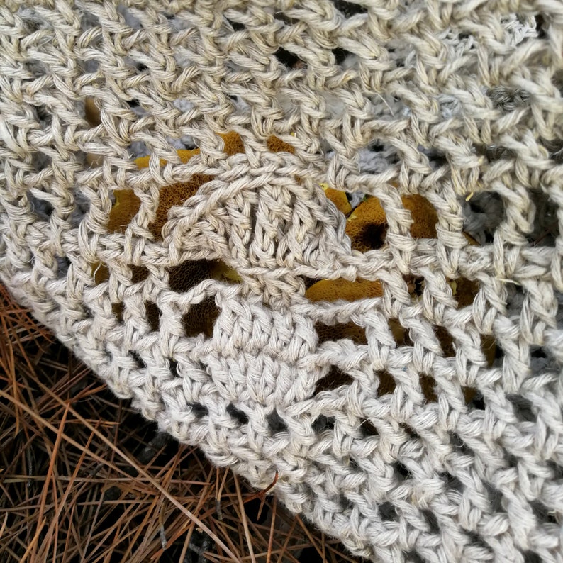 A close up photo of one of the mushrooms crocheted into the bag. It has a rounded top with a straight edge underneath and a stem which is narrower at the top than the bottom. The stem also has a rounded bottom.