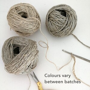 Three balls of yarn around the top left corner of the photo each are a different shade. From beige to light grey and warm grey. Grey text on a white background says Colours vary between batches