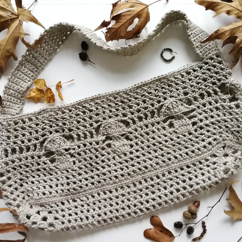 The mushroom bag is sat on a white background with autumnal leaves, acorns and dried flowers scattered around it. The 3 mushrooms can be seen more clearly here. The strap of the bag is about 2 inches wide.