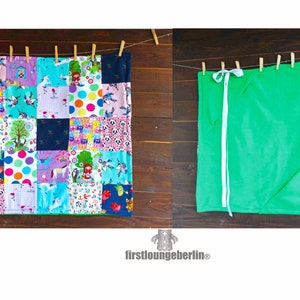 May include: Two fabric blankets hanging on a clothesline. The blanket on the left is a patchwork quilt with a variety of colorful patterns and designs. The blanket on the right is a solid green color. The text "firstloungeberlin" is visible in the bottom center of the image.