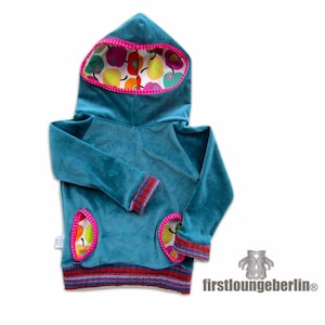 Puede incluir: Sudadera con capucha azul turquesa con forro de estampado de frutas coloridas en la capucha y los bolsillos. La sudadera tiene una banda a rayas alrededor de la parte inferior y los puños.