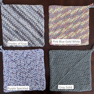 May include: Four crocheted pot holders in different color combinations.  The pot holders are square shaped with a diagonal stitch pattern.  The colors are: Shades of Gray, Pink Blue Gold White, Purple Speckled, and Gray Solid.